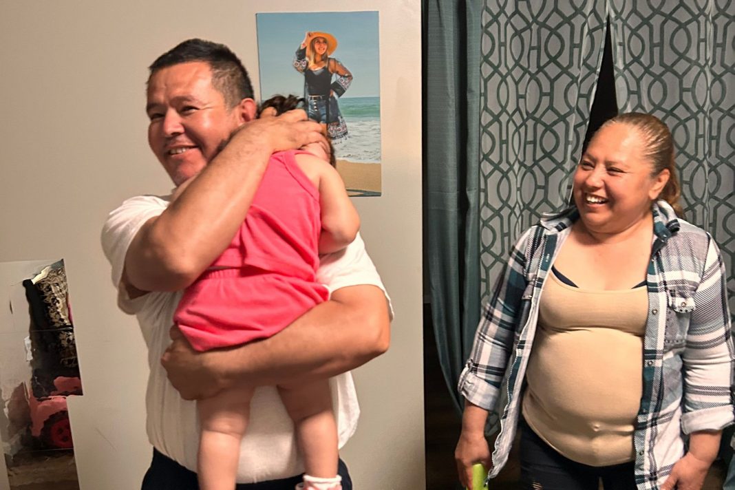 Erasmo Zavala hugs his granddaughter, Selene, as his wife Maria stands nearby. A picture of Selene’s mother, Selena, who was murdered, hangs behind the family. May 29, 2026.