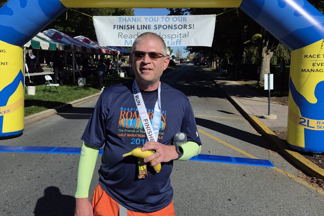 Adam Hughes celebrates a major milestone at Reading Hospital Road Run after crossing the finish line of his 50th half marathon.